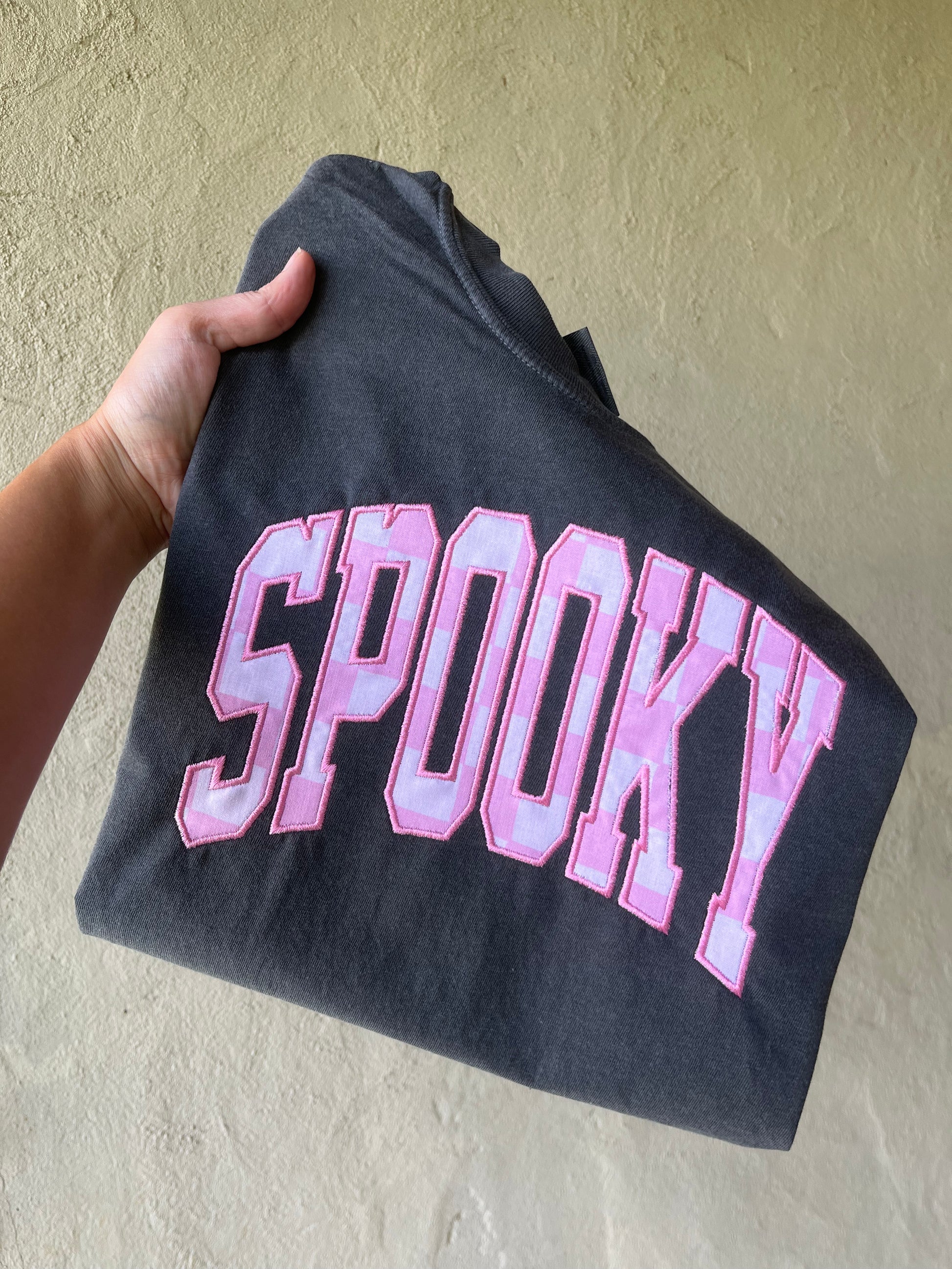 Black t-shirt with 'Spooky' in pink checker letters 